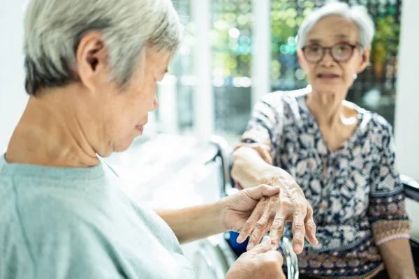 Asian elderly woman massaging palm and fingers of friend  senior or sister having heumatoid arthritis, beriberi,peripheral neuropathies,old people suffer from hand numbness,muscle pain,sore,achy hand — 스톡 사진