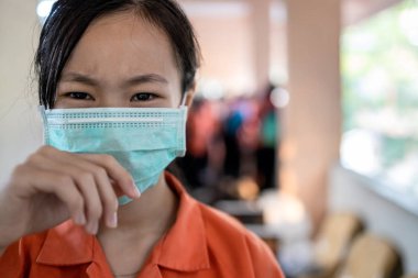 Hasta Asyalı öğrenci Tayland okul üniforması giyip hijyenik maske, sağlık, toz, hava kirliliği, Pm2.5, virüs koruması, Bangkok 'ta okulda koruyucu maske takan korkmuş bir kadın.