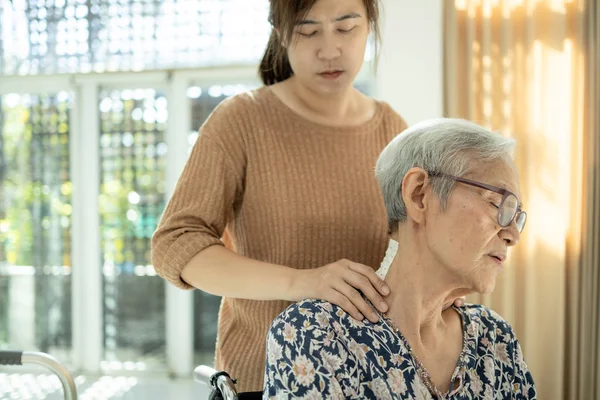 Asiatische Seniorin hat Nervenschmerzen, Schulterschmerzen, Nackenschmerzen, Pflegerin oder Tochter massiert ihre Schultern, frustrierte ältere Frau fühlt sich erschöpft, Nackenschmerzen, Muskelkater, Entzündungen — Stockfoto