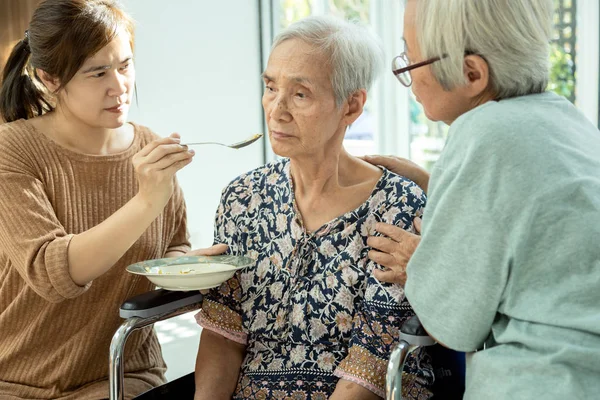 Asiatin ernährt müde Seniorin, Magersucht, isst weniger, depressive ältere Frauen leiden unter depressiven Störungen, Depressionen, Appetitlosigkeit, Schlaflosigkeit, Langeweile bei alten Menschen, — Stockfoto