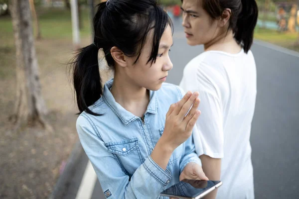 Distracted child girl looking at phone,addicted to playing games on mobile phone,crashed into adult woman while walking on street,carelessness of asian teenage with female people bump into each other