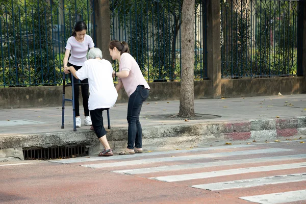 Unavená asijské senior žena s chodítkem se snaží vylézt na chodník po přechodu přes silnici na přechodu, čelí obtíže, bariéra, vysoká pěšina, různé úrovni podlahy, problémy postižených starších — Stock fotografie