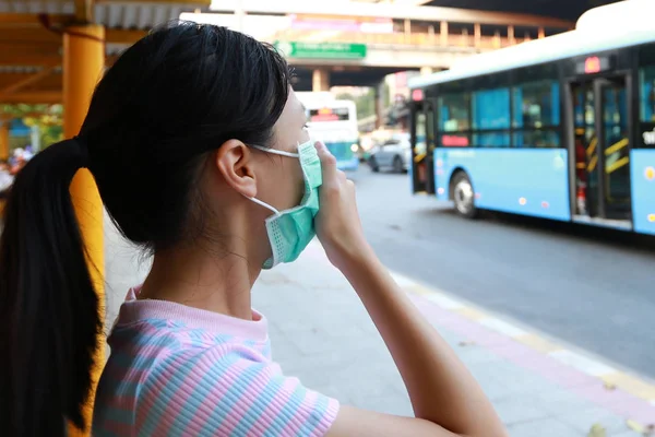 Nemocné asijské dítě dívka nosí ochrannou masku proti znečištění ovzduší na autobusové zastávce ve městě Bangkok, vdechovat jemný prach, pm 2.5, ženské lidi pomocí obličejové masky chránit své zdraví před znečištěním smog — Stock fotografie