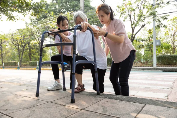 Asiática mãe e filha ajuda, cuidado, apoiar avó sênior ao ar livre após atravessar a estrada, barreira de caminho, calçada é alta, área de nível diferente, idosos com andador, dor nas pernas, problema de estilo de vida — Fotografia de Stock