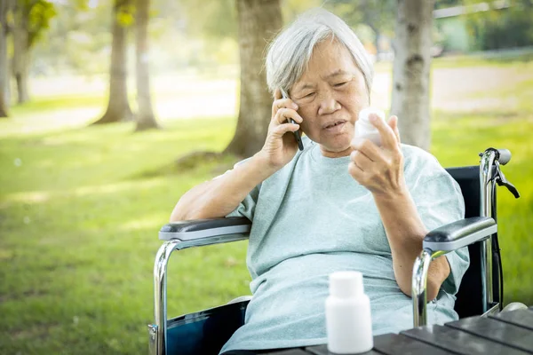 Kranke asiatische Seniorin hält Flasche mit Medikamenten — Stockfoto