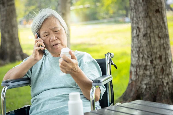 Sjuk asiatisk äldre kvinna som håller flaska medicin — Stockfoto