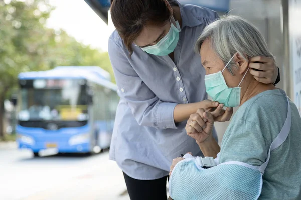 Азійка, одягнена в медичну маску для старшої особи, тому що хвора жінка похилого віку з кашлем і гарячкою, запобігає поширенню мікробів для інших людей на автобусній зупинці, Коронавірус, Мерс-Ков, Вухан Вірус 2019-ncov. — стокове фото
