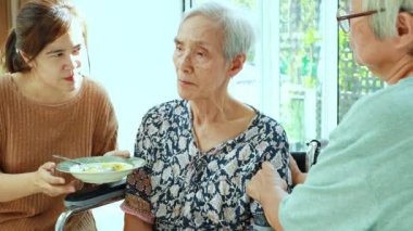 Asyalı kadın yorgun yaşlı hastayı besliyor, iştahsızlık çekiyor, daha az yemek yiyor, depresyondaki yaşlı kadın depresyon belirtileri, iştah kaybı, uykusuzluk, yaşlılarda yemekten sıkılmış.