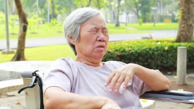 Asian senior woman has sleepy expression,female elderly yawning covering open mouth with hand,old people feel yawn,doze,sleepy in outdoor park,being tired after sleepless night,lack of sleep concept