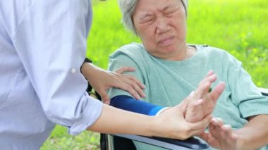 Injured asian senior woman wearing elbow support suffering from sore muscle,elbow joint arm pain,female caregiver do not intend to massage hard,unhappy elderly with elbow protector pads feeling hurt