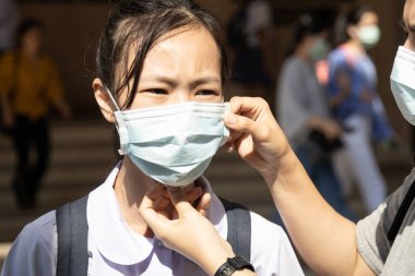 Halk arasında hastalık riski altında tıbbi maske takan Asyalı kız çocuğu, Wuhan Çin 'de Coronavirus 2019-ncov enfeksiyonunun yayılmasını, grip, nezle ve grip mevsimlerinin korunmasını engelliyor.  