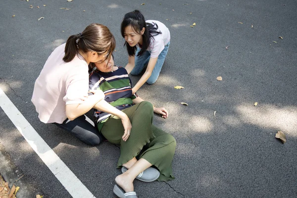 屋外公園の地面に横たわっている病気のアジアの高齢者の女性は心臓病に苦しんでおり、女性の高齢者は鬱血性心不全、脳卒中、意識不明、健康問題で床に落ちた — ストック写真