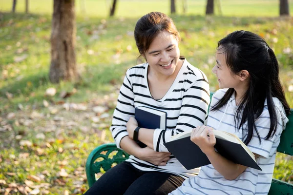 Child girl reading book and adult woman enjoy together at summer park,loving daughter holding book sit on bench having fun,reading story book and telling story to mother,happy asian family,lifestyle — Stock Photo, Image