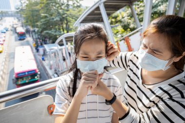 Hasta Asyalılar koruyucu maske takıyor, çocuk kızda öksürük, hava kirliliği, zehirli toz, duman, ince toz, Bangkok 'ta hava kirliliği veya PM2.5, solunum sistemi için tehlike