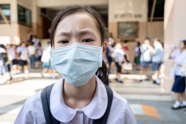 Okulda koruyucu maske takan Asyalı çocuk öğrenci, salgın hastalık, Coronavirus, Covid-19, Corona virüsü bulaşmasını önlemek için maskeli kız öğrenci, Covid-19 salgınıyla mücadele ediyor.