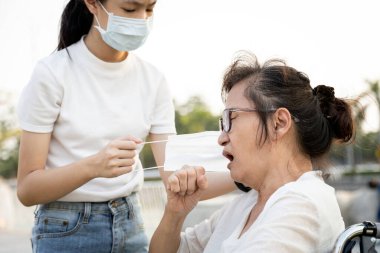 Asyalı torun bakımı, büyük anneye yardım, öksürük, çocuk ve yaşlı insanlar hava kirliliği, Covid-19 salgını, Coronavirus yayılması nedeniyle maske takıyor. 