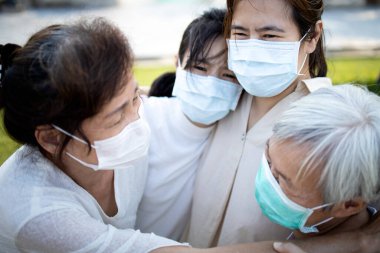 Tıbbi maske takan üzgün Asyalı aile ağlıyor, yas tutuyor, ailesinin büyük bir kaybı enfekte olmuş, Covid-19, Coronavirus salgınıyla mücadele ediyor, insanlar salgın krizini, sarılmayı, rahatlamayı, teşvikleri etkiliyor.