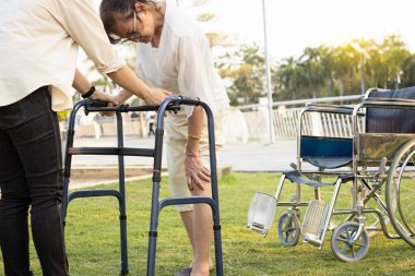 Kıdemli Asyalı kadın hasta elinin dizine dokunması, eklem ağrısı, kemik problemi, yürürken dizlerinde ağrı, rehabilitasyon sırasında yürüteç, yaşlı kadın osteoporoz, gut, raşitizm.