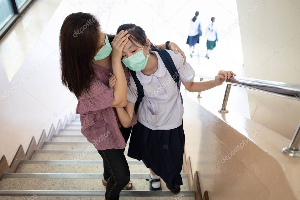 Exhausted asian child girl with illness and fever,girl wear face mask,has vertigo,dizziness or symptoms of the Coronavirus,Covid-19 infection,flu and cold,feel tired,sick woman is fainting unconscious