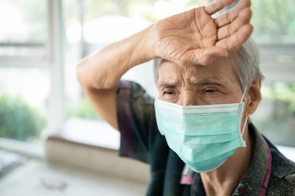 亚洲老年生病妇女摸着额头 检查体温 疾病和发烧 疲倦的老年患者戴着面具 有感冒 感染症状的科罗纳韦勒斯或科维德19型 — 图库照片