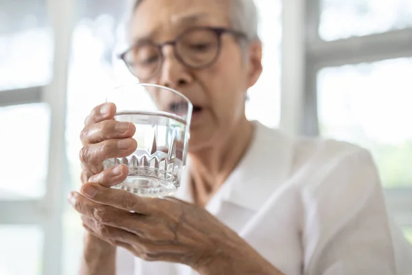 老年妇女拿着一杯水 一边喝水一边握手 年龄较大的病人手颤抖 身体不受控制的颤动 基本颤动的症状 帕金森病 神经紊乱 — 图库照片