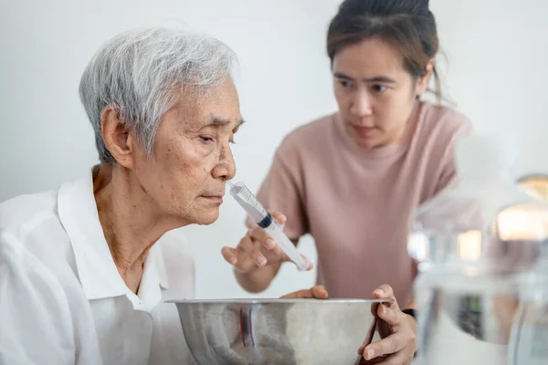 아시아 세척제를 만들고 주사기와 식염수로 어머니를 알레르기 감기나 — 스톡 사진