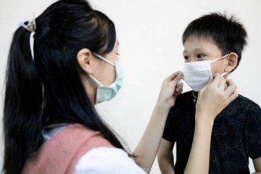 Çocuk ya da abla okula dönerken erkek kardeşlerinin grip ve hastalıklarını önlemek için maske takıyor. Dönem başlıyor. Covid-19 enfeksiyonu riski olan çocuk, Coronavirus salgını.