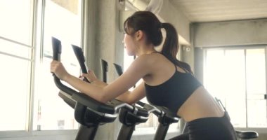 Durağan bisikletli çekici Asyalı kadın jimnastik salonunda dönüyor. Ağır çekim. Sağlık, Egzersiz ve Spor Konsepti.