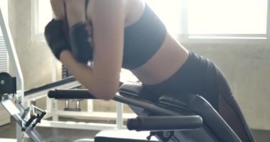 Genç sporcu Asyalı kadın spor salonundaki antrenör sırt uzatma makinesinde aşırı genişleme egzersizleri yapıyor. Ağır çekim. Egzersiz ve Spor kavramı.