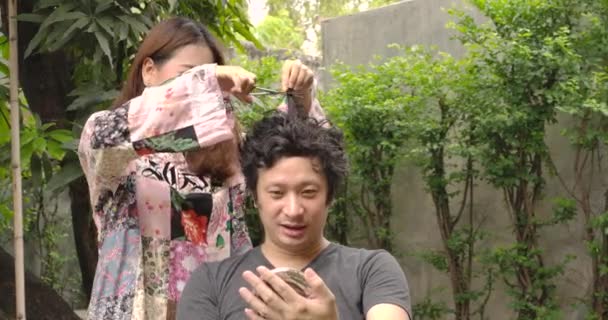 Młoda Azjatka Próbująca Obciąć Włosy Swojemu Chłopakowi Lub Mężowi Nożyczkami — Wideo stockowe