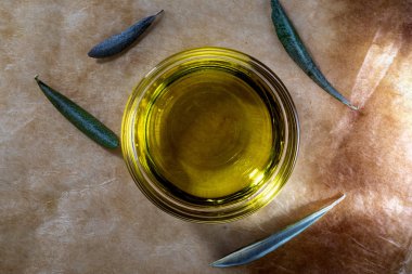 Cam kasede ekstra saf zeytinyağı. İçinde zeytin yaprakları var. Kırsal arka plan. Üst görünüm.