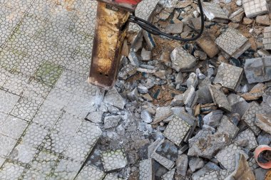 Kazı makinesinin hidrolik çekiçli yakın çekimi şehirdeki bir kaldırımdan çimento ve fayanslar kaldırıyor. Bayındırlık İşleri (resim dizisi)