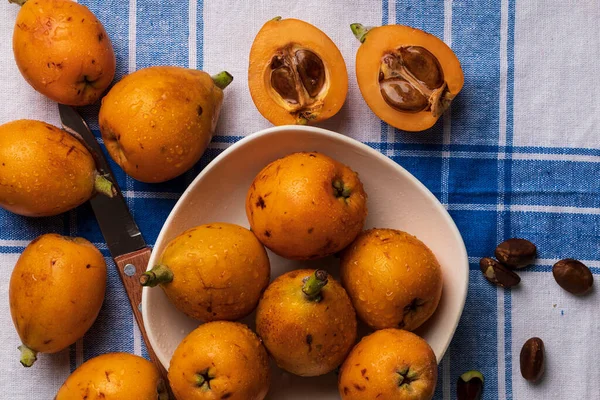 Taze loquats (medlars) mavi damalı masa örtüsü arka plan Rustik ve sağlıklı bir görünüm. Close-up.Top görünümü.
