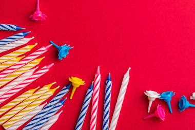 Kırmızı arka planda doğum günü mumları grubu. Doğum günü tebrik kartı için. Metin eklemek için boşluk. Çok renkli, mavi, kırmızı, sarı ve beyaz.