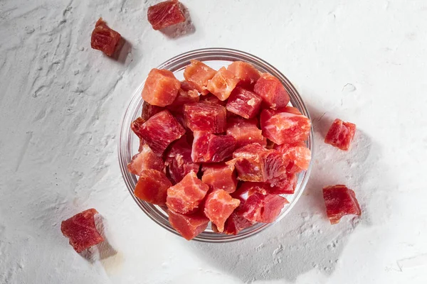 İber jambonu (Serrano) küp şeklinde kesilmiş. Cam bir kasede. Beyaz desenli arkaplan.