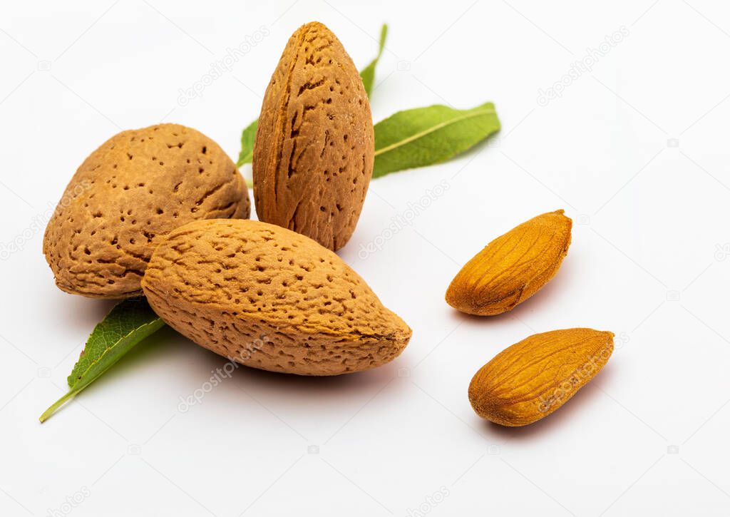 Raw almonds, peeled, with peel, skin (almendrucos) and almond leaves. Isolated on white background.