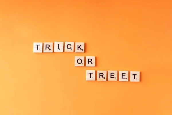 Letras de madeira com truque de texto ou treet em fundo laranja. Halloween. — Fotografia de Stock