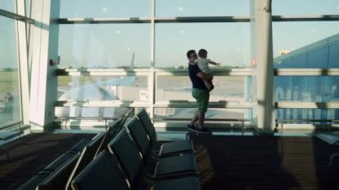 Baba ve oğul camdan uçaklara bakıyor. Bebekle havaalanına git.