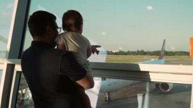 Baba ve oğul camdan uçaklara bakıyor. Bebekle havaalanına git.