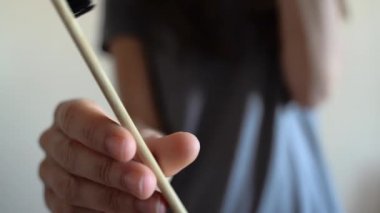 Kadın eline yakın çekim bambu diş fırçasını gösteriyor. Sıfır atık, banyo, plastiksiz.