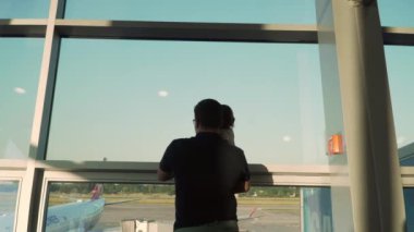 Baba ve oğul camdan uçaklara bakıyor. Bebekle havaalanına git.