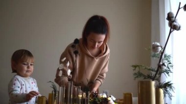 Kadın elinin köknar dallarıyla Noel çelengi yapması ve ışık tutması. Anne ve bebek.