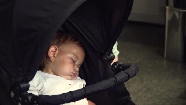 Little baby girl is sleeping in stroller indoors in summer hot weather. Travelling with toddler — Stock Video