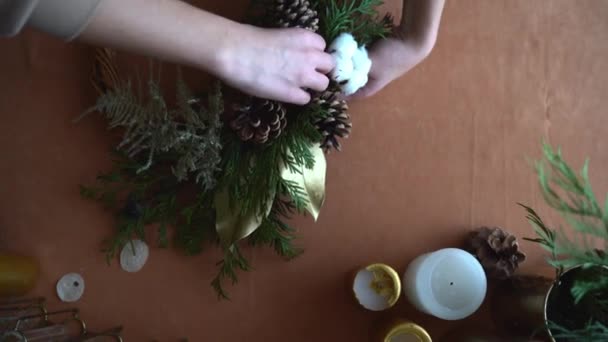Vista superior de las manos floristas haciendo corona de Navidad con ramas de abeto y luz led. Vista superior, cero residuos — Vídeos de Stock