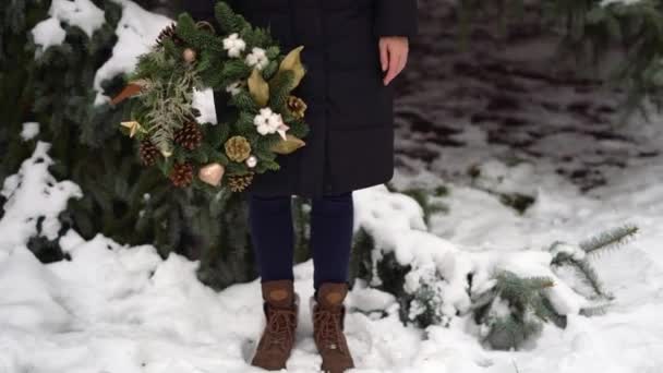 手にクリスマスリースを持つ少女のブーツの足。冬の雪の日 — ストック動画