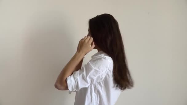 Vnitřní portrét mladé ženy sbírající vlasy v culíku, oblečené v bílé košili. Ranní jednoduchá rutina — Stock video