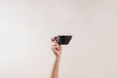 Hand with black cup with coffee. Morning rituals. Sleepy mood. Minimal