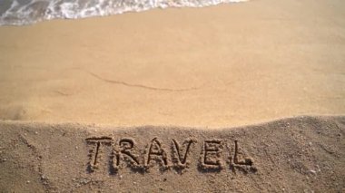 Vacation concept on the beach. Word Travel written on the sand near the sea. Copy space