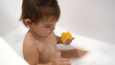 Bir bebek köpük ve sabun köpüğüyle banyo yapar.