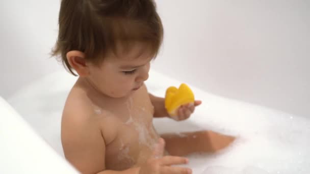 Uma menina toma banho em um banho com espuma e bolhas de sabão — Vídeo de Stock